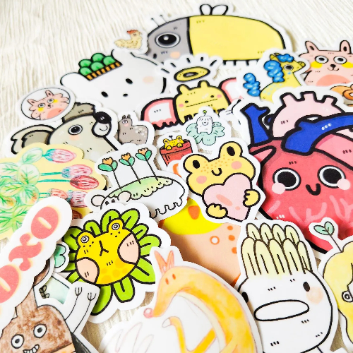 Kuvassa on läjä 2-laatuisia tarroja. Tarrat ovat värikkäitä eläimiä ja muita hassuja olentoja.