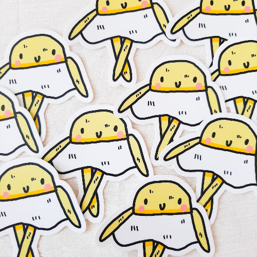 Kuvassa oleva tarra on keltainen kananmuna. Kananmunan valkuainen on olennon vartalo, ja valkuaisosuus laskeutuu aivan kuin hame. Kananmunalla on iloinen ilme.