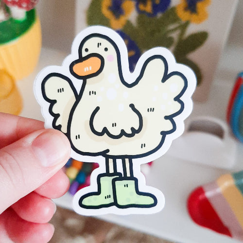 Kuvassa oleva ankka on vaaleankeltainen, ja sillä on iso oranssi nokka. Ankalla on hauskat, vihreät saappaat jalassa. Ankka on värikäs ja hulvaton.