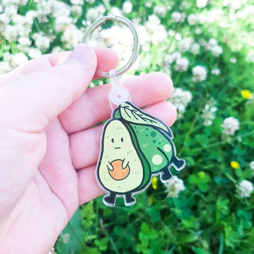 Avaimemenperä, jossa on kaksi toisissaan kiinni olevaa avokadoa. Vain toiselta näkyy etupuoli. Tämä avokado on tympäätyneen oloinen. Selkä katsojaan olevalla avokadolla sen sijaan näkyy pyllyvako.