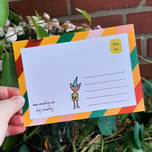 Kuvassa on postikortin takaosa. Takaosassa on samat värit kuin etuosassa ja siellä seiikkailee tonttu.