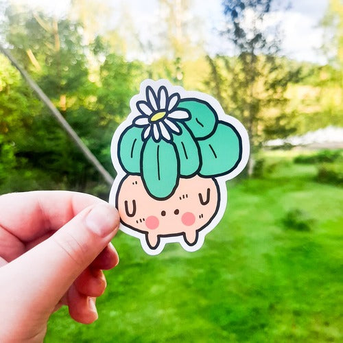 Vedenkestävä kukkateemainen vinyylitarra. Tarra on sipulimainen olento, jolla on vaaleanpunainen vartalo. Sen päässä kasvaa lehtiä ja valkoinen, upea kukka.