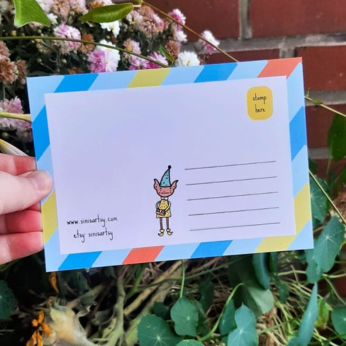 Kuvassa on postikortin takaosa. Takaosassa on samat värit kuin etuosassa ja siellä seiikkailee tonttu.