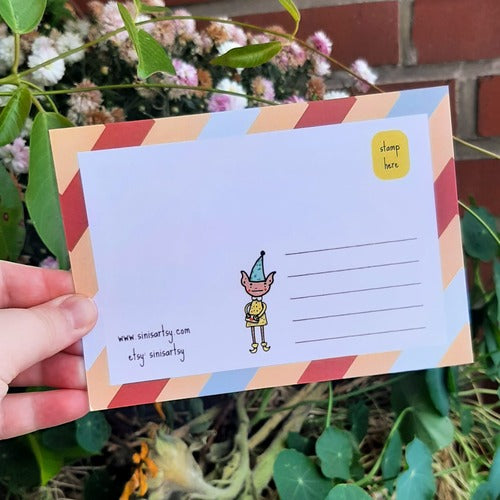 Kuvassa on postikortin takaosa. Takaosassa on samat värit kuin etuosassa ja siellä seiikkailee tonttu.