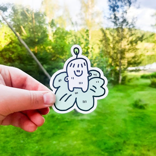 Kuvassa on hauska kasvitarra. Siinä on valkoinen mönttimäinen olento seisomassa vihreän, itseä suuremman lehden päällä. Olennolla on iloinen ilme ja sen päästä kasvaa lehti.