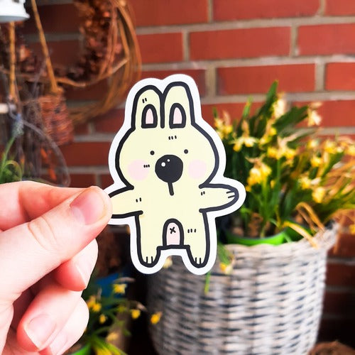 Kuvassa oleva hauska vedenkestävä tarra on vaalean beige pupu. Pupulla on vaaleanpunainen maha ja posket, ja sillä näkyy napa. Pupun kädet ovat kuin valmiina halaukseen.