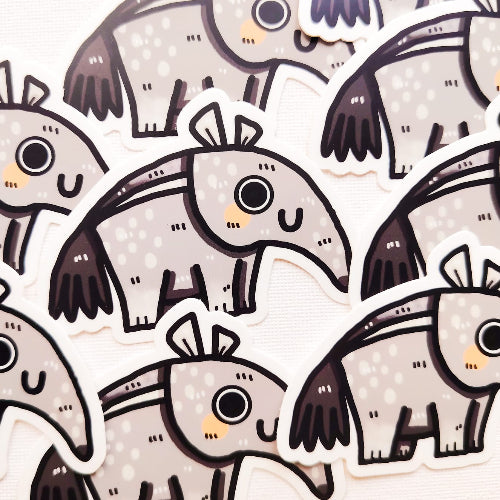 Kuvassa on harmaa muurahaiskarhutarra. Muurahaiskarhulla on iloinen ilme, punaiset posket ja hauskat korvat.