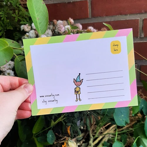 Kuvassa on postikortin takaosa. Takaosassa on samat värit kuin etuosassa ja siellä seiikkailee tonttu.