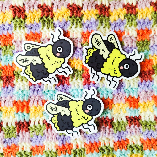 Vedenkestävä vinyylitarra, joka on keltamusta ampiainen. Se on oikein pörröinen ja sillä on isot silmät ja vahvat siivet. Pörriäinen hymyilee.